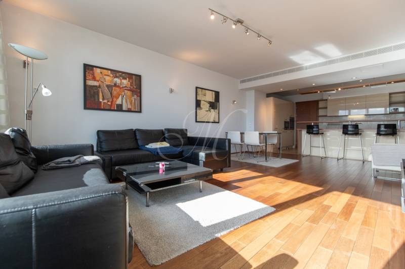 Moderný 2-izbový byt s balkónom, Eurovea - Obývačka v 2-izbovom byte s podlahou s dreveným dekorom a čiernym koženým gaučom.