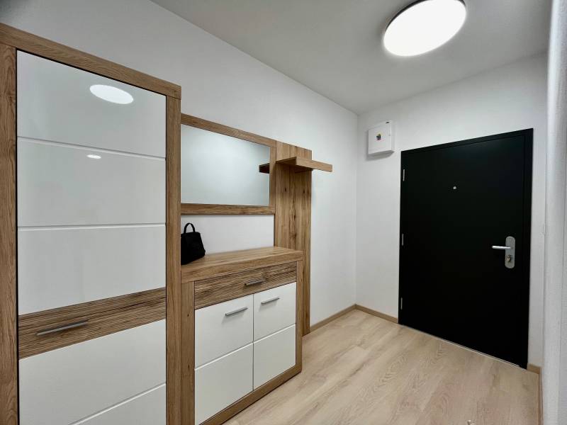 PRENÁJOM NOVOSTAVBA 2 izb.byt, BALKÓN, PARKOVACIE MIESTO, BIELY KOSTOL - Chodba s podlahou s dreveným dekorom v 2-izbovom byte, moderný nábytok a tmavé dvere.