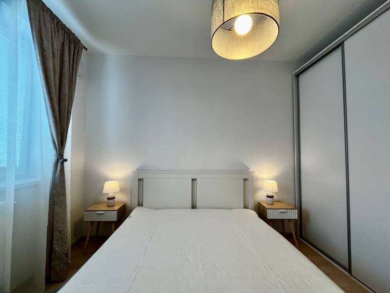 PRENÁJOM NOVOSTAVBA 2 izb.byt, BALKÓN, PARKOVACIE MIESTO, BIELY KOSTOL - Spálňa v 2-izbovom byte s bielou posteľou, nočnými stolíkmi a lampami.