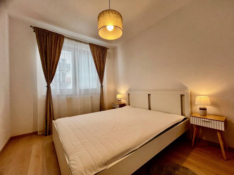 PRENÁJOM NOVOSTAVBA 2 izb.byt, BALKÓN, PARKOVACIE MIESTO, BIELY KOSTOL - Spálňa s veľkou posteľou, závesmi a podlahou s dreveným dekorom v 2-izbovom byte.