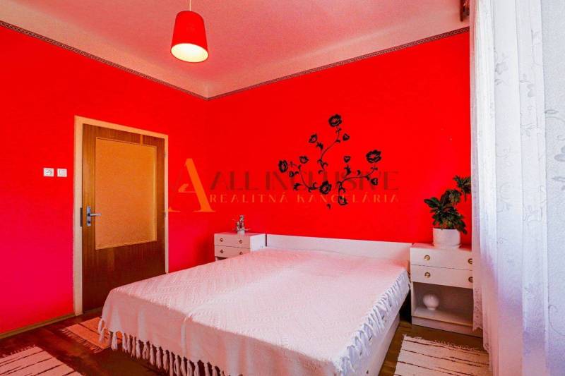 NA PREDAJ 7 IZBOVÝ RODINNÝ DOM, DUNAJSKÁ STREDA - Spálňa v rodinnom dome s červenými stenami, posteľou a dekoráciou na stene.