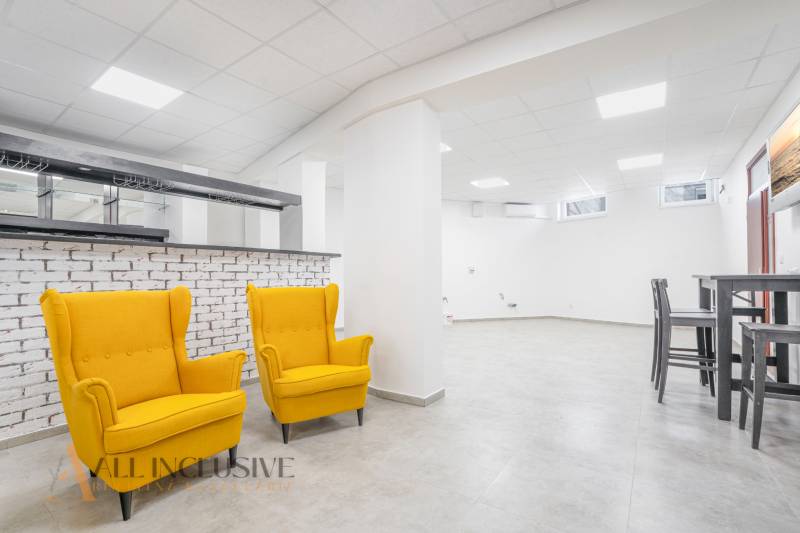 NA PRENÁJOM OBCHODNÝ PRIESTOR-KANCELÁRIA ,DUN. STREDA - Interiér s dvoma žltými kreslami, biely stĺp, barová stena a stolík s dvoma stoličkami.