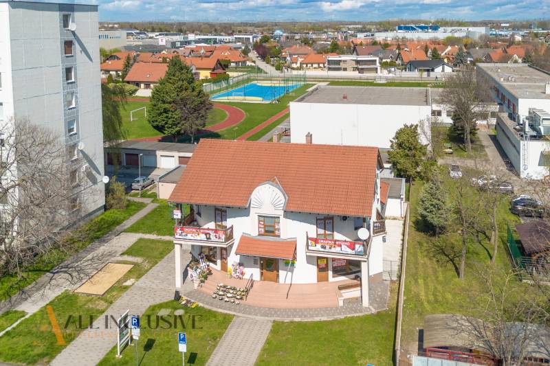 NA PRENÁJOM OBCHODNÝ PRIESTOR-KANCELÁRIA ,DUN. STREDA - Budova s červenou strechou na ulici Jilemnického, obklopená zeleňou a športoviskom, kancelárie.