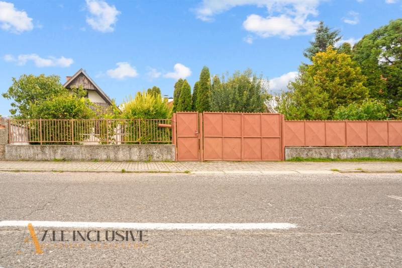 NA PREDAJ 2-IZBOVÝ RODINNÝ DOM S PODKROVÍM, BODÍKY - Rodinný dom v Bodíkoch s bránou, oploteným pozemkom a zeleňou na pozadí.