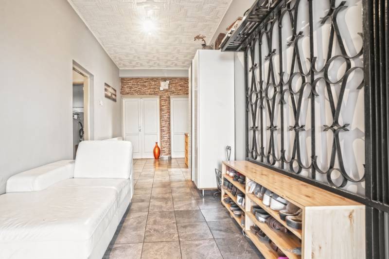 NA PREDAJ VÝNIMOČNÝ RODINNÝ DOM VO VEĽKOM MEDERI - Interiér rodinného domu s bielou pohovkou, stenou s dekorom a botníkom.