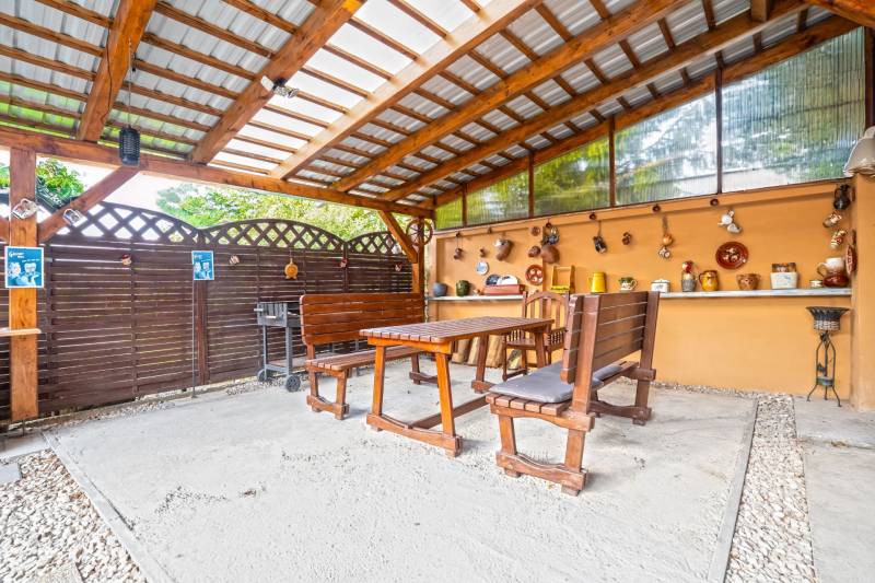 NA PREDAJ VÝNIMOČNÝ RODINNÝ DOM VO VEĽKOM MEDERI - Krytá terasa v rodinnom dome vo Veľkom Mederi s dreveným sedením a dekoráciami.