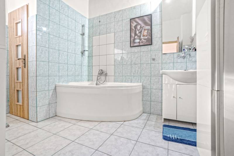 NA PREDAJ VÝNIMOČNÝ RODINNÝ DOM VO VEĽKOM MEDERI - Kúpeľňa v rodinnom dome s rohovou vaňou, umývadlom a obkladmi v modrých odtieňoch.