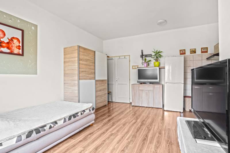 NA PREDAJ VÝNIMOČNÝ RODINNÝ DOM VO VEĽKOM MEDERI - Obývacia izba s rozkladacím gaučom, skriňou a podlahou s dreveným dekorom v rodinnom dome.