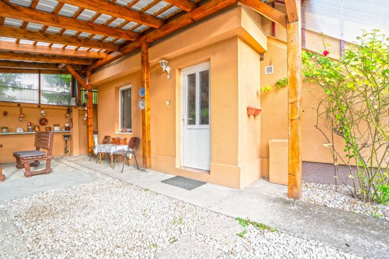 NA PREDAJ VÝNIMOČNÝ RODINNÝ DOM VO VEĽKOM MEDERI - Zastrešená terasa rodinného domu vo Veľkom Mederi s drevenými konštrukciami a posedovou zónou.