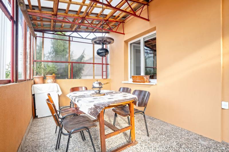 NA PREDAJ VÝNIMOČNÝ RODINNÝ DOM VO VEĽKOM MEDERI - Zastrešená terasa so stolom a stoličkami v rodinnom dome.