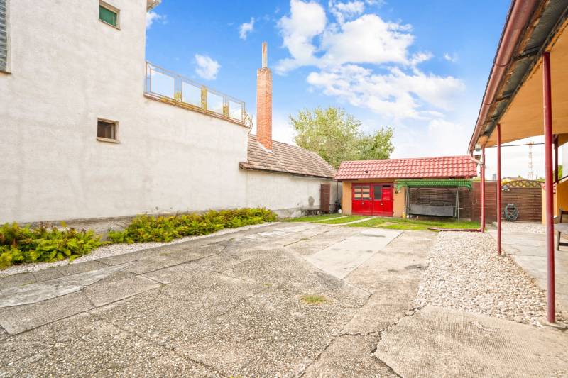 NA PREDAJ VÝNIMOČNÝ RODINNÝ DOM VO VEĽKOM MEDERI - Nádvorie rodinného domu vo Veľkom Mederi s prístavbou a trávnatou plochou.