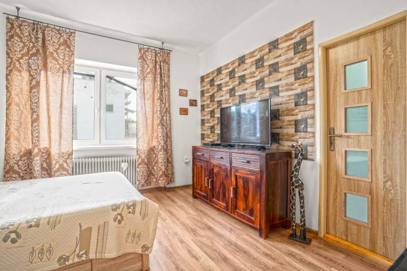 NA PREDAJ VÝNIMOČNÝ RODINNÝ DOM VO VEĽKOM MEDERI - Spálňa v rodinnom dome so stenou s tehlovým obkladom a podlahou s dreveným dekorom.