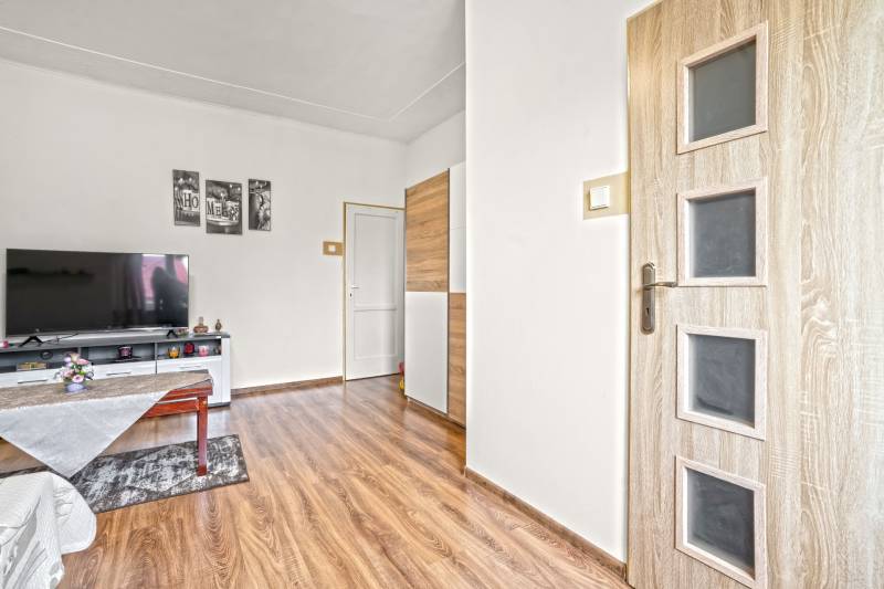 NA PREDAJ VÝNIMOČNÝ RODINNÝ DOM VO VEĽKOM MEDERI - Obývacia izba v rodinnom dome s TV a podlahou s dreveným dekorom.