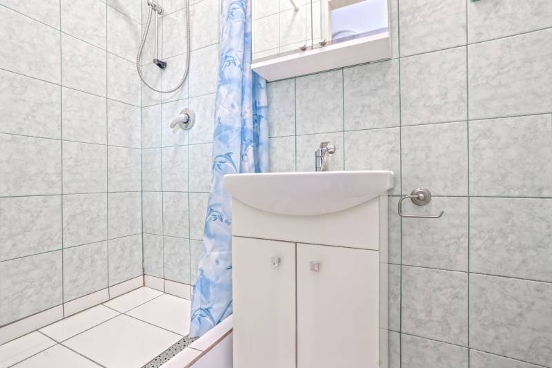 NA PREDAJ VÝNIMOČNÝ RODINNÝ DOM VO VEĽKOM MEDERI - Kúpeľňa v rodinnom dome s bielym umývadlom, sprchou a modrým závesom.