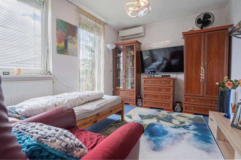 NA PREDAJ 3 IZBOVÝ RODINNÝ DOM, KĽÚČIAROVÉ KRAČANY - Obývačka v rodinnom dome s pohovkou, posteľou, televízorom a dreveným nábytkom.