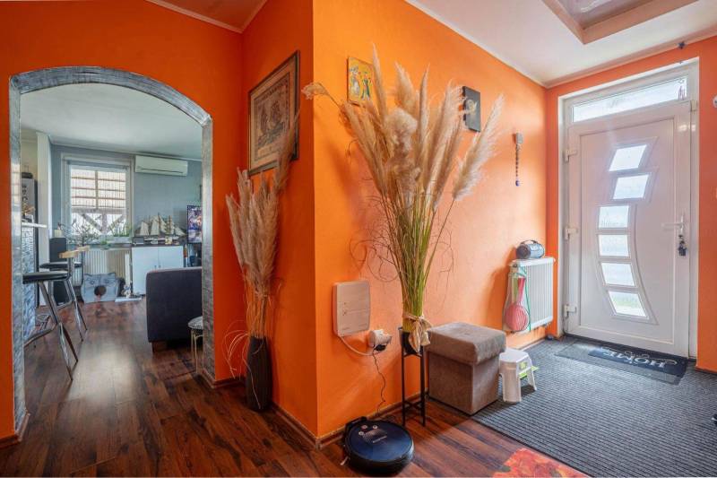 NA PREDAJ 3 IZBOVÝ RODINNÝ DOM, KĽÚČIAROVÉ KRAČANY - Chodba s oranžovými stenami, bielymi dverami a podlahou s dreveným dekorom v rodinnom dome.