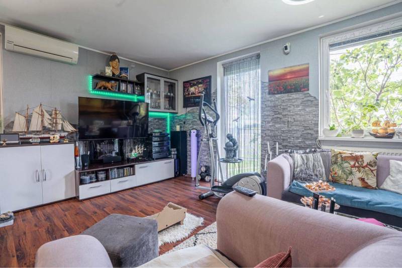 NA PREDAJ 3 IZBOVÝ RODINNÝ DOM, KĽÚČIAROVÉ KRAČANY - Svetlá obývačka v rodinnom dome s pohovkou a podlahou s dreveným dekorom.