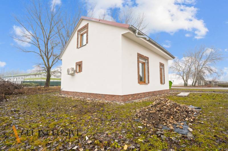 NA PREDAJ 4-IZBOVÉ RD – REZIDENČNÝ PROJEKT, GABČÍKOVO - Rodinný dom v Gabčíkove s omietkovou fasádou a tehlovým obkladom, na trávnatom pozemku.