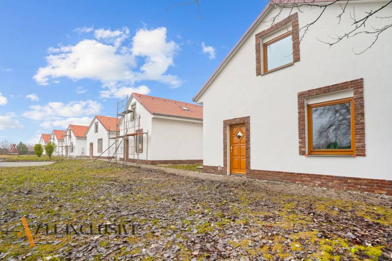 NA PREDAJ 4-IZBOVÉ RD – REZIDENČNÝ PROJEKT, GABČÍKOVO - Rodinné domy v Gabčíkove s bielou fasádou, pred nimi zelený trávnik a modrá obloha.