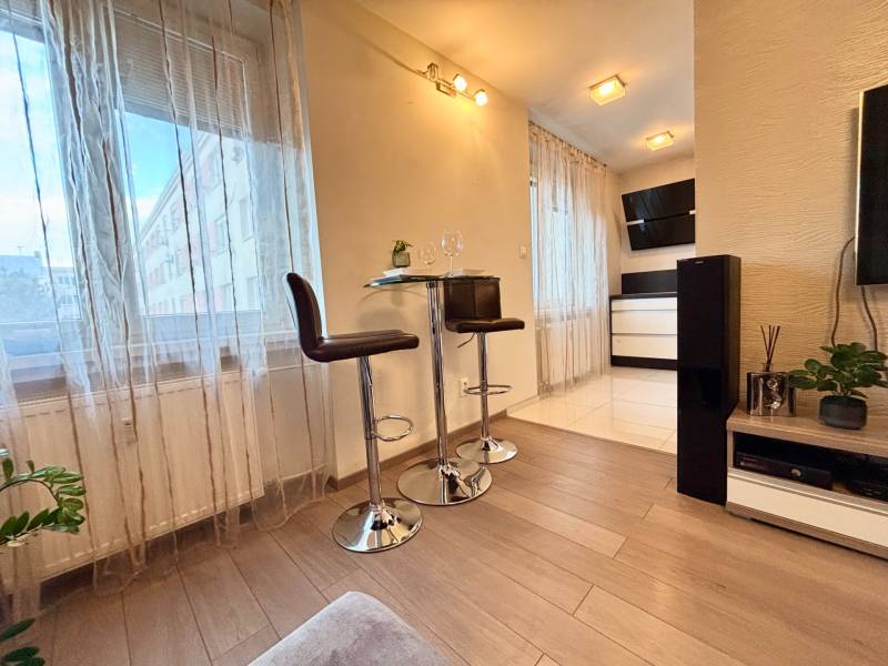 Štýlový, zariadený 2- izbový byt s balkónom pri stanici!!! - Interiér 2-izbového bytu s podlahou s dreveným dekorom, barovými stoličkami a dekoráciami.