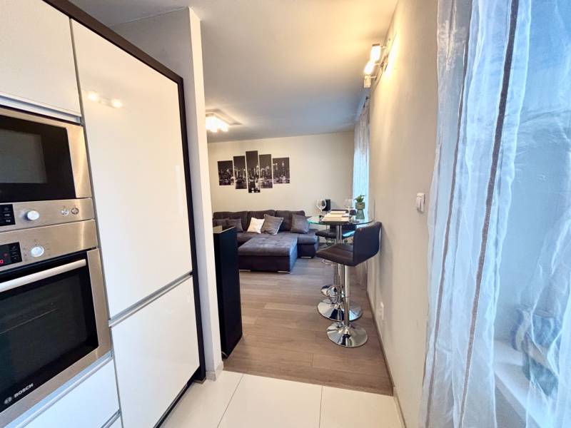 Štýlový, zariadený 2- izbový byt s balkónom pri stanici!!! - Kuchynský kút so spotrebičmi, barovým sedením a pohľadom na obývačku v 2-izbovom byte.