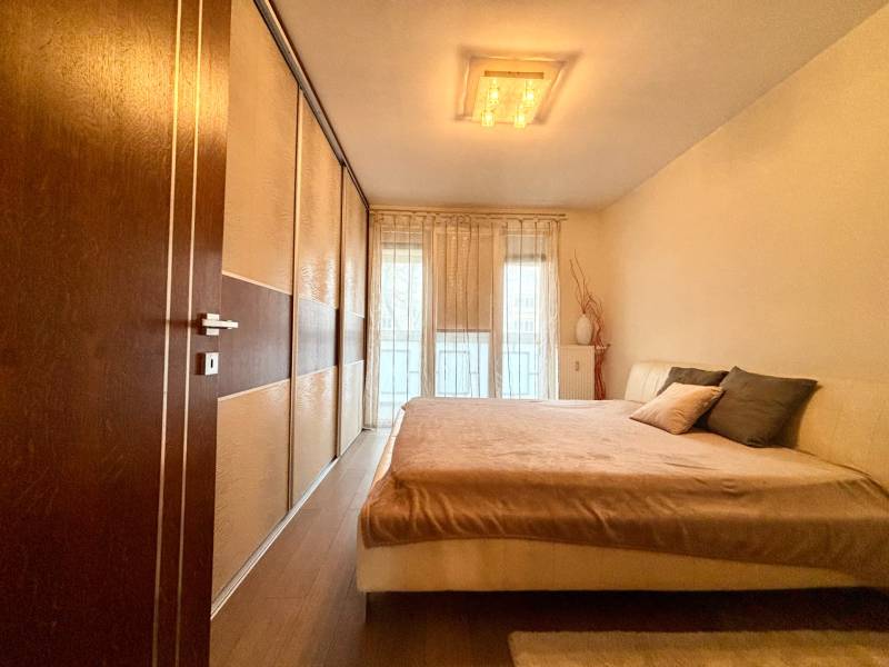 Štýlový, zariadený 2- izbový byt s balkónom pri stanici!!! - Spálňa v 2-izbovom byte s veľkou posteľou a podlahou s dreveným dekorom.