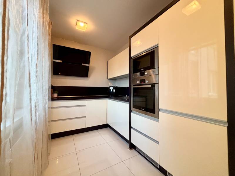 Štýlový, zariadený 2- izbový byt s balkónom pri stanici!!! - Biela kuchyňa s čiernymi akcentmi a spotrebičmi v 2-izbovom byte.