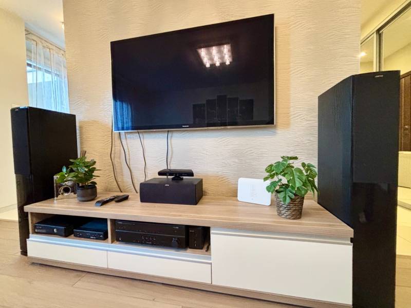 Štýlový, zariadený 2- izbový byt s balkónom pri stanici!!! - Televízor na stene obývačky s dekoračnými rastlinami a elektronikou na skrinke.