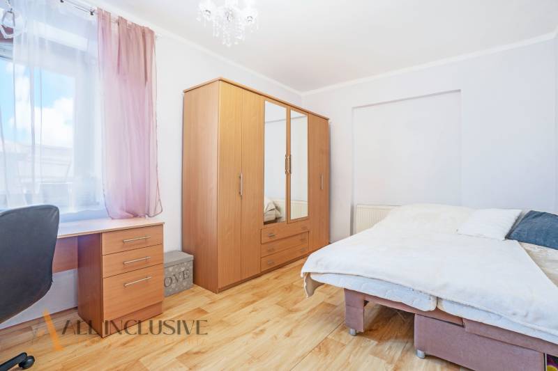 ZNÍŽENÁ CENA | NA PREDAJ DVOJGENERAČNÝ RODINNÝ DOM, AMADE KRAČANY - Svetlá spálňa s dreveným nábytkom, pracovným stolom a veľkou posteľou na ulici Amade Kračany.