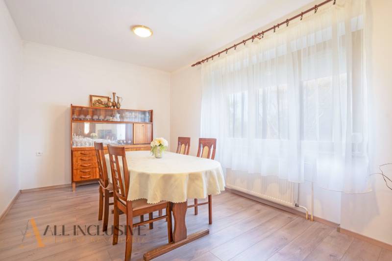 ZNÍŽENÁ CENA | NA PREDAJ DVOJGENERAČNÝ RODINNÝ DOM, AMADE KRAČANY - Jedáleň v rodinnom dome, ulica Amade Kračany, drevený nábytok, okno s bielymi závesmi.