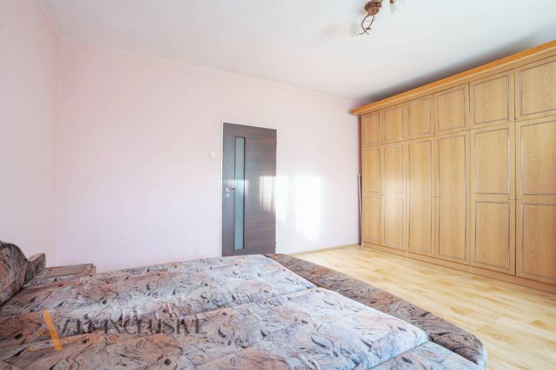 ZNÍŽENÁ CENA | NA PREDAJ DVOJGENERAČNÝ RODINNÝ DOM, AMADE KRAČANY - Spálňa s drevenou skriňou, svetloružovou stenou a dvojitým posteľným poťahom.