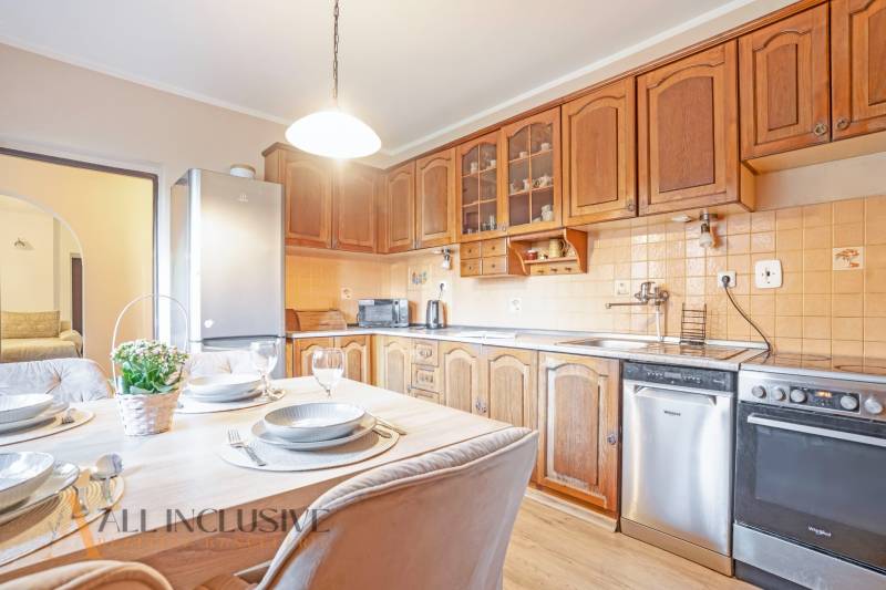 ZNÍŽENÁ CENA | NA PREDAJ DVOJGENERAČNÝ RODINNÝ DOM, AMADE KRAČANY - Kuchyňa s jedálenským stolom, drevenými skrinkami a spotrebičmi v rodinnom dome na ulici Amade Kračany.