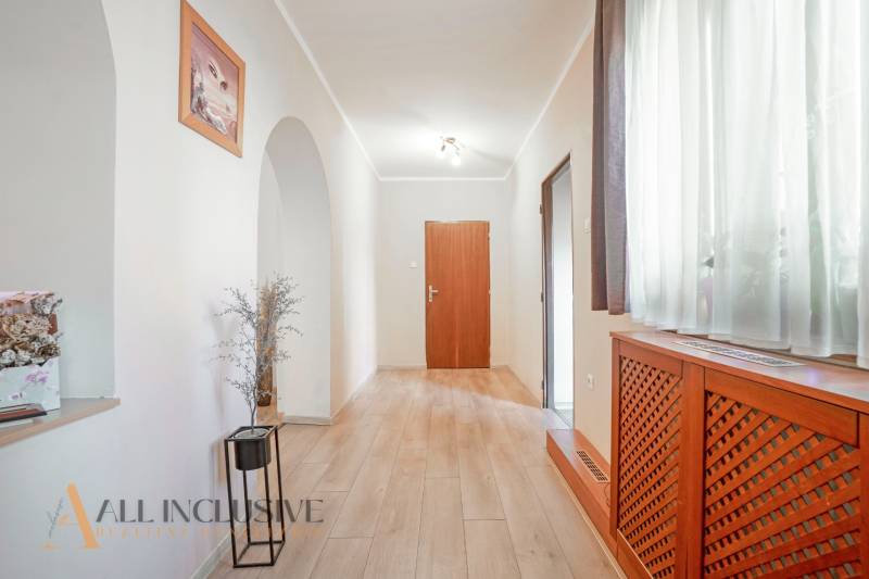 ZNÍŽENÁ CENA | NA PREDAJ DVOJGENERAČNÝ RODINNÝ DOM, AMADE KRAČANY - Chodba s drevenou podlahou a rastlinou, súčasť rodinného domu na ulici Amade Kračany.