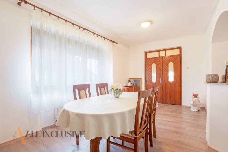 ZNÍŽENÁ CENA | NA PREDAJ DVOJGENERAČNÝ RODINNÝ DOM, AMADE KRAČANY - Jedáleň v rodinnom dome na ulici Amade Kračany s dreveným nábytkom a bielymi závesmi.