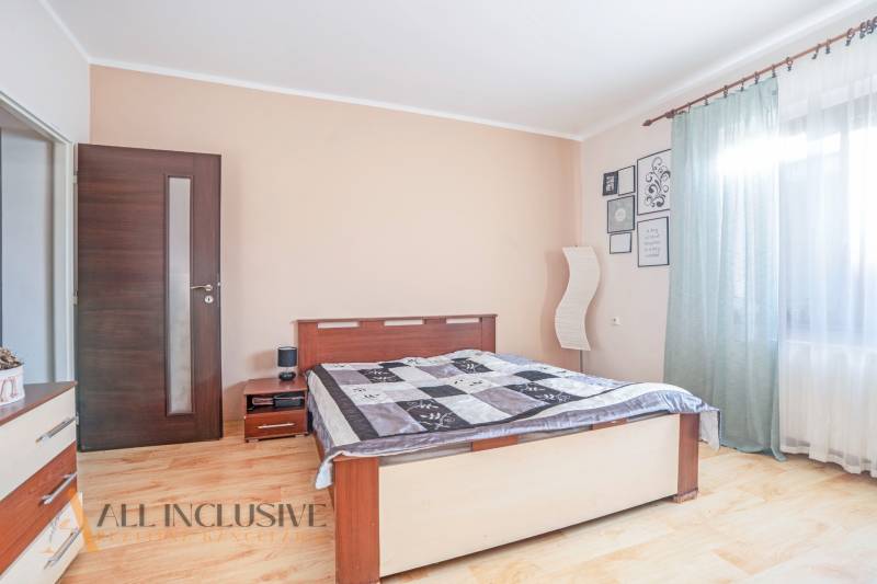 ZNÍŽENÁ CENA | NA PREDAJ DVOJGENERAČNÝ RODINNÝ DOM, AMADE KRAČANY - Spálňa v rodinnom dome s drevenou podlahou, veľkým oknom a svetlými závesmi.