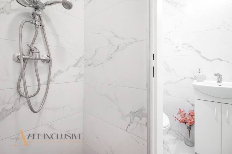 NA PREDAJ 2-IZBOVÝ BYT V CENTRE MESTA DUNAJSKÁ STREDA - Sprchová hlavica a umývadlo s kvetmi v kúpeľni v 2-izbovom byte na ulici Biskupa Kondého.