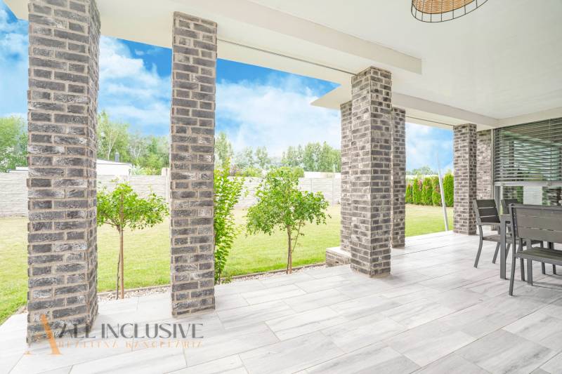 NA PREDAJ NADŠTANDARDNÁ 4-IZB. NOVOSTAVBA, DUN. KLÁTOV - Terasa rodinného domu v Dunajskom Klátove s tehlovými stĺpmi a záhradným nábytkom.