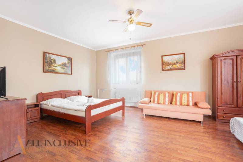 NA PREDAJ PENZIÓN VO VEĽKOM MEDERI – SUNGARDEN - Interiér izby v hoteloch a penziónoch s drevenou posteľou, sedačkou a obrazmi.