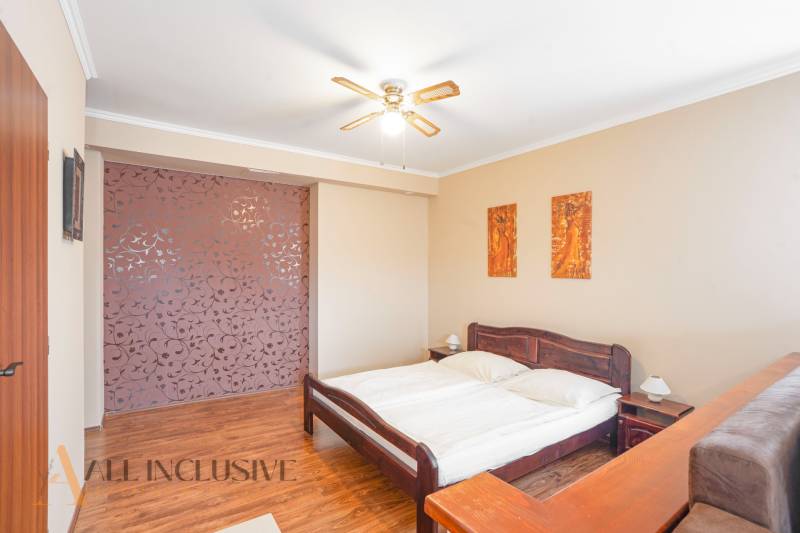 NA PREDAJ PENZIÓN VO VEĽKOM MEDERI – SUNGARDEN - Spálňa s drevenou posteľou, ventilátorom a dekoračnými obrazmi v hoteloch a penziónoch.