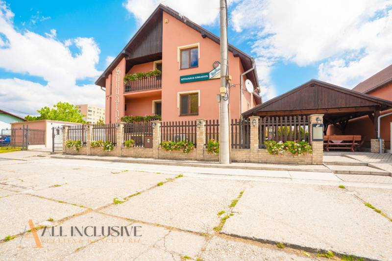 NA PREDAJ PENZIÓN VO VEĽKOM MEDERI – SUNGARDEN - Budova s reštauráciou a penziónom v meste Veľký Meder, lemovaná plotom.