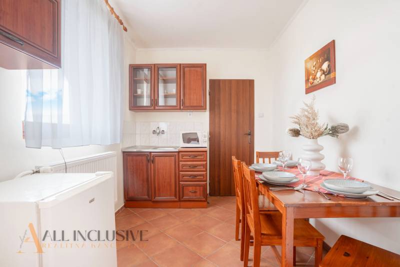 NA PREDAJ PENZIÓN VO VEĽKOM MEDERI – SUNGARDEN - Kuchynka v Hoteloch a penziónoch s drevenými skrinkami, stolom a dekoráciou na stole.