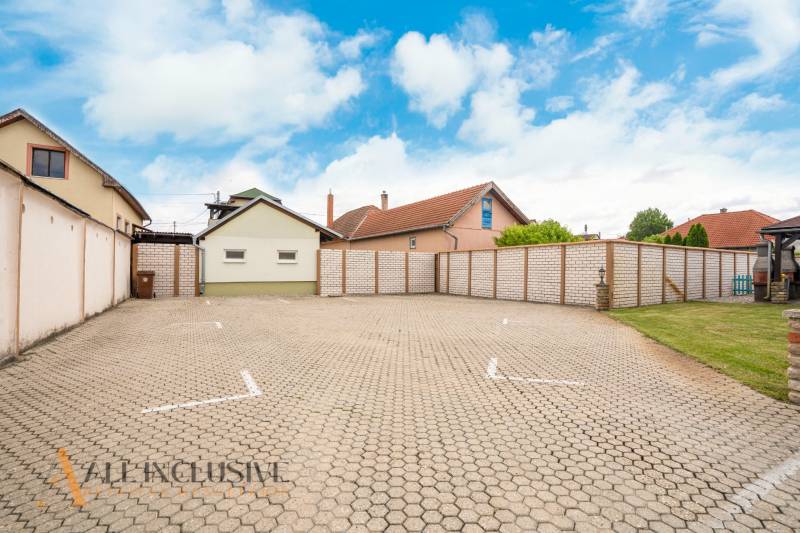 NA PREDAJ PENZIÓN VO VEĽKOM MEDERI – SUNGARDEN - Parkovisko v Hoteloch a penziónoch vo Veľkom Mederi s okolitými budovami a oblohou.