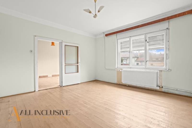 REZERVOVANÉ 4-IZBOVÝ RODINNÝ DOM, TOPOĽNÍKY - Izba rodinného domu s podlahou s dreveným dekorom, bielymi stenami a presklenými dverami.