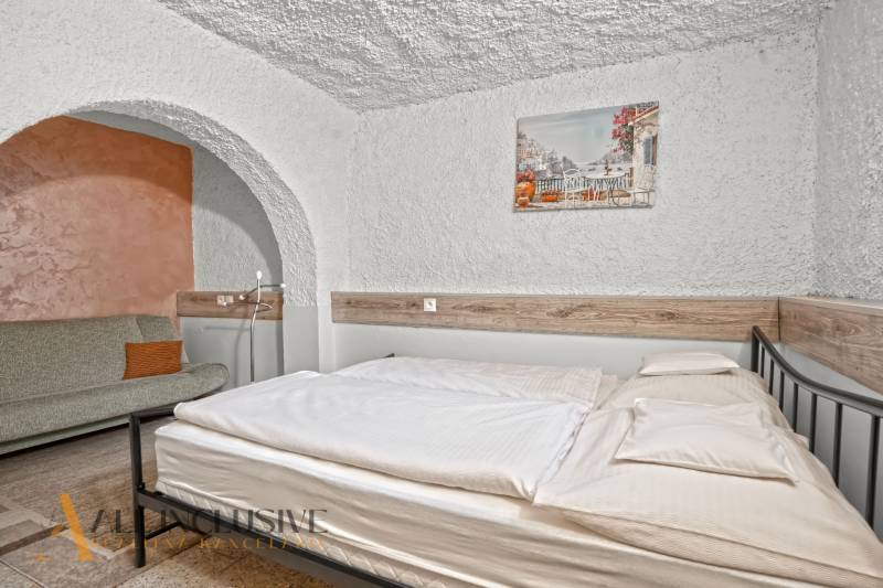 NA PREDAJ APARTMÁNOVÝ DOM VO VEĽKOM MEDERI - Posteľ a pohovka v izbe s oblúkom, podlaha s dreveným dekorom. Hotely a penzióny.