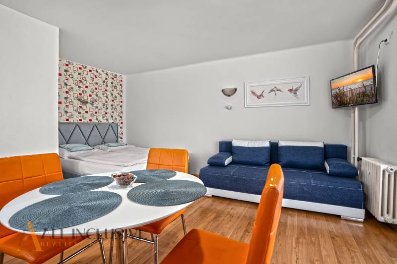 NA PREDAJ APARTMÁNOVÝ DOM VO VEĽKOM MEDERI - Interiér izby v hoteloch a penziónoch s podlahou s dreveným dekorom, posteľou a sedačkou.