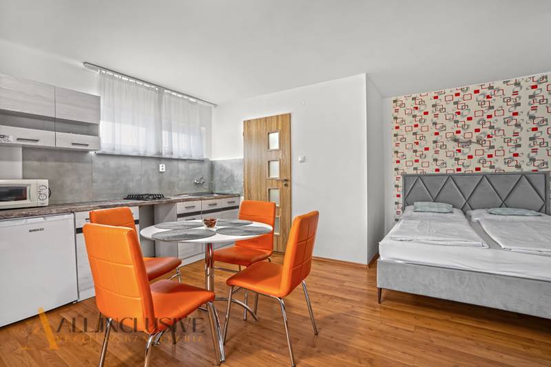 NA PREDAJ APARTMÁNOVÝ DOM VO VEĽKOM MEDERI - Pokoj v hoteloch a penziónoch s oranžovými stoličkami, kuchynským kútom a posteľou.