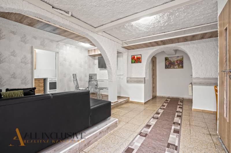 NA PREDAJ APARTMÁNOVÝ DOM VO VEĽKOM MEDERI - Interiér s čiernou sedačkou, stolom, stoličkami a oblúkovými priechodmi v Hotely a penzióny.