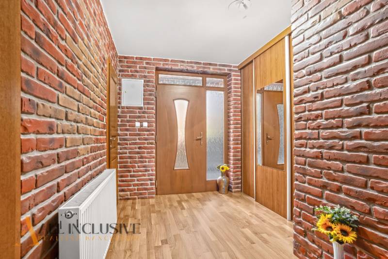 NA PREDAJ 6-IZBOVÝ POSCH. RODINNÝ DOM, HORNÉ SALIBY - Vstupná chodba s tehlovými stenami a podlahou s dreveným dekorom v rodinnom dome.