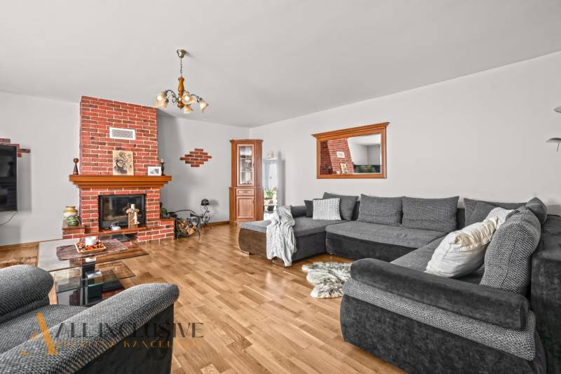 NA PREDAJ 6-IZBOVÝ POSCH. RODINNÝ DOM, HORNÉ SALIBY - Obývacia izba v rodinnom dome s krbom, šedým gaučom a podlahou s dreveným dekorom.