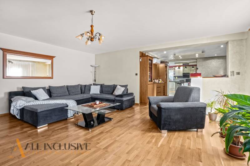 NA PREDAJ 6-IZBOVÝ POSCH. RODINNÝ DOM, HORNÉ SALIBY - Obývacia izba v rodinnom dome s veľkou sedacou súpravou, podlahou s dreveným dekorom a rastlinami.